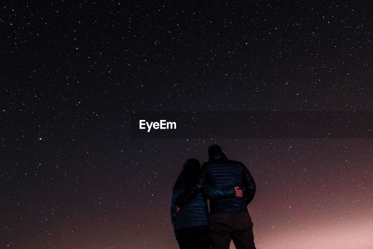 Low angle view of couple standing against star field