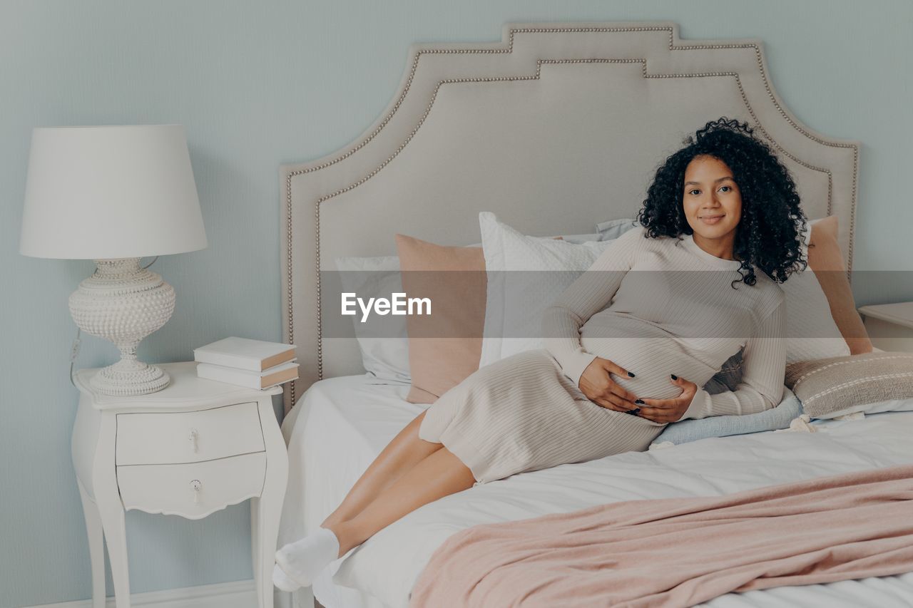 YOUNG WOMAN SITTING ON BED