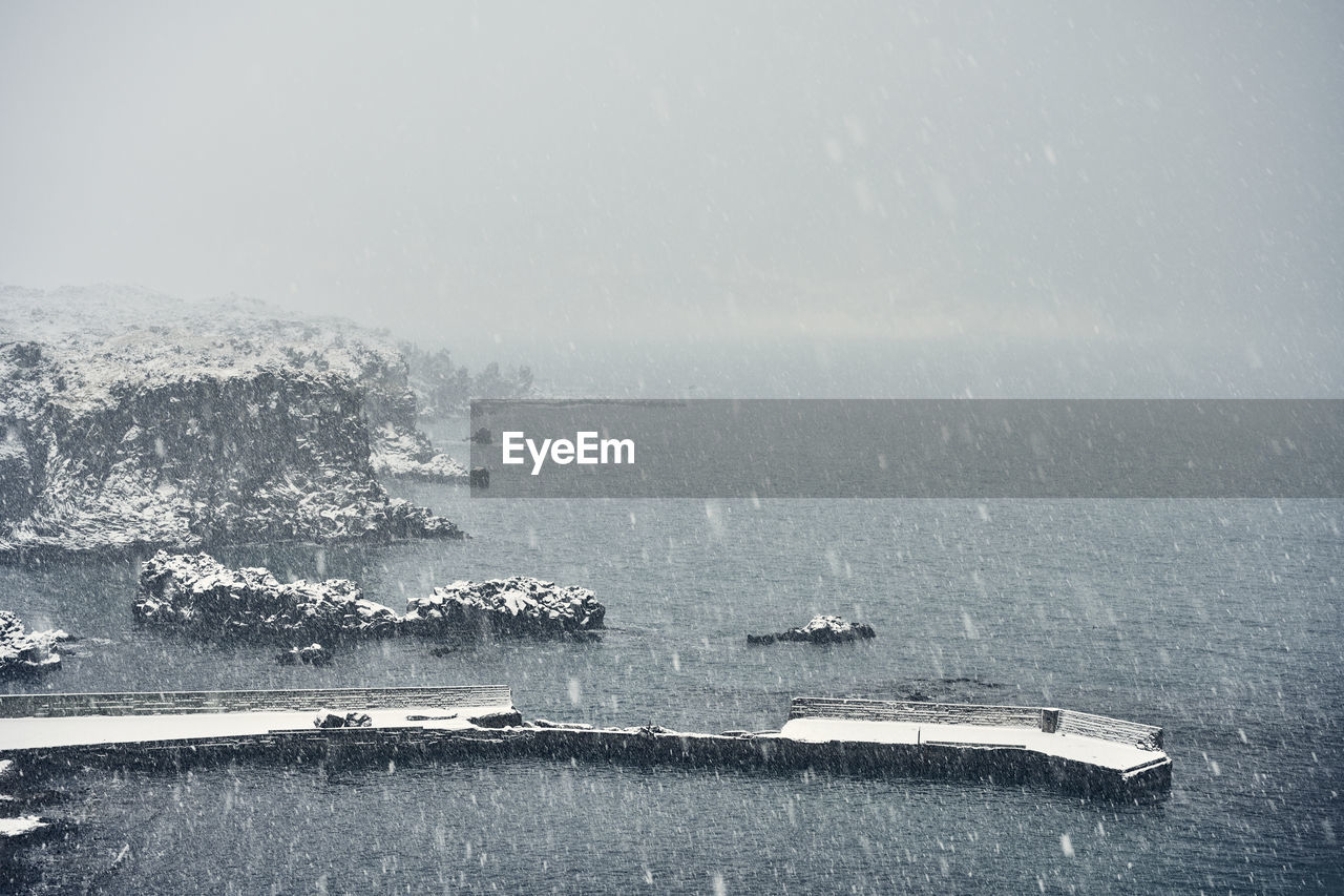 Picturesque seascape with cliff during snowy weather