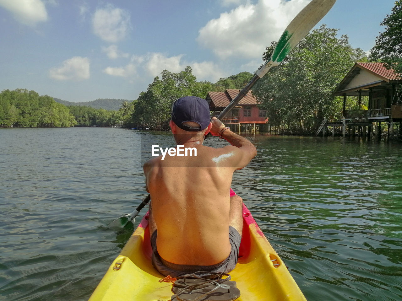 REAR VIEW OF SHIRTLESS MAN IN WATER