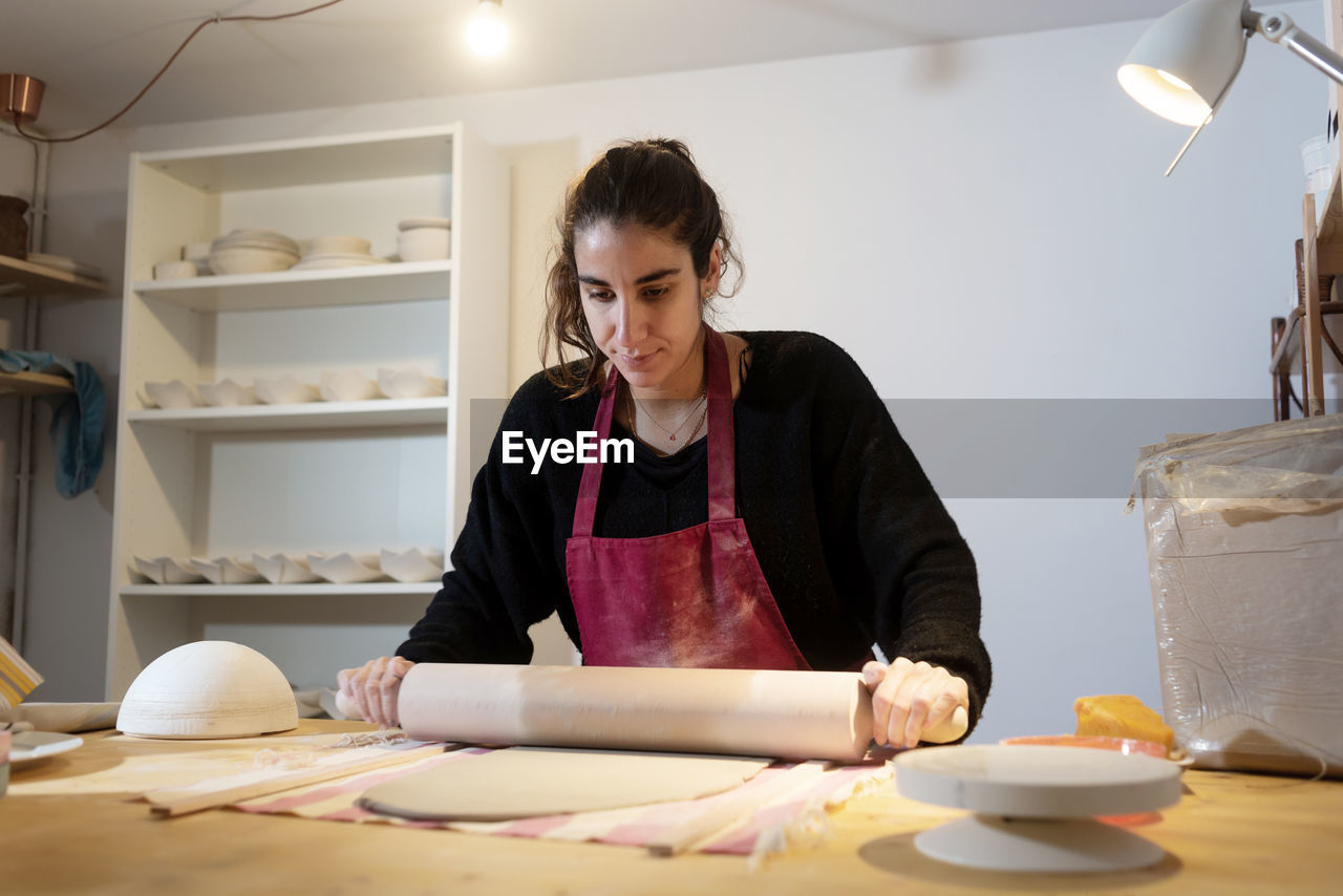 Women using a rolling pin roll out the clay for a ceramic plate