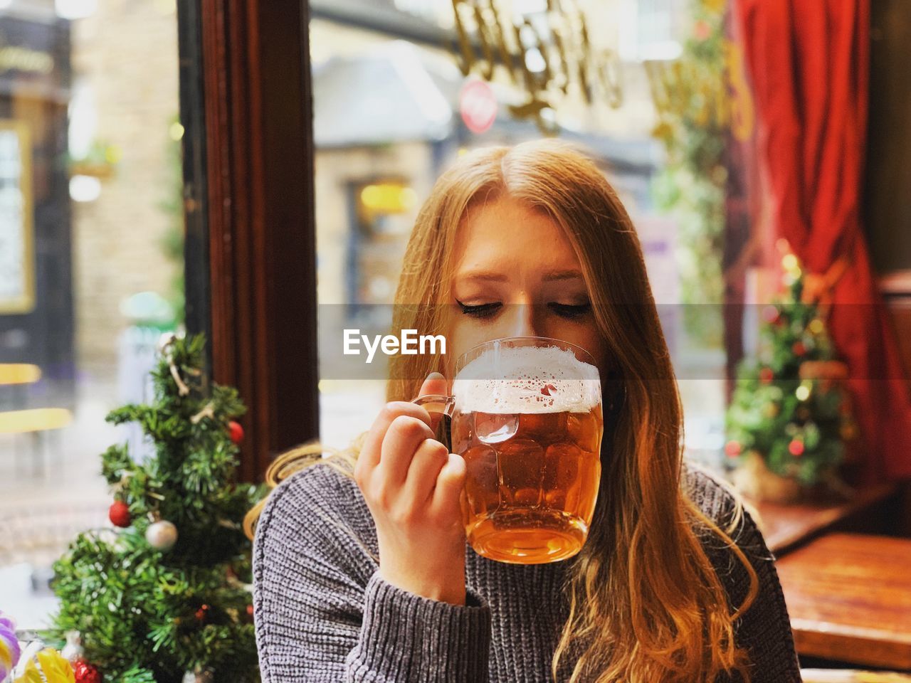 Woman drinking beer in glass at restaurant