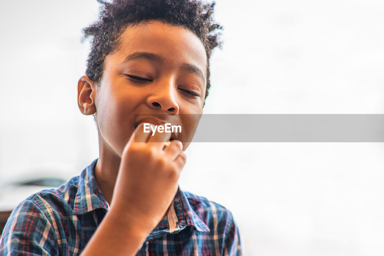 Boy with eyes closed eating food