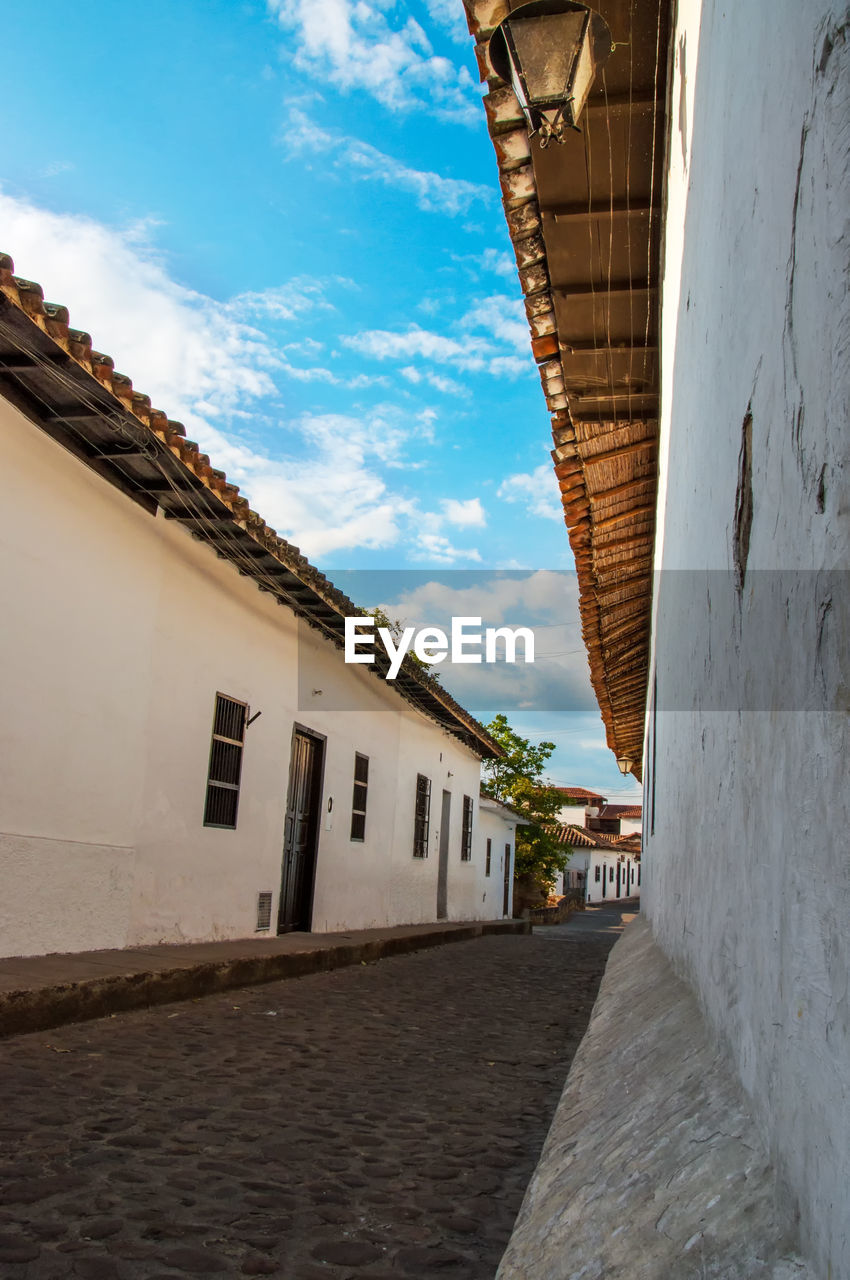 Empty cobblestone street amidst houses in town