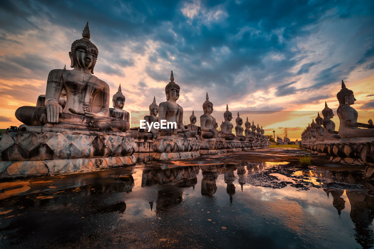 Statue of ancient buddha statues against sky during sunset