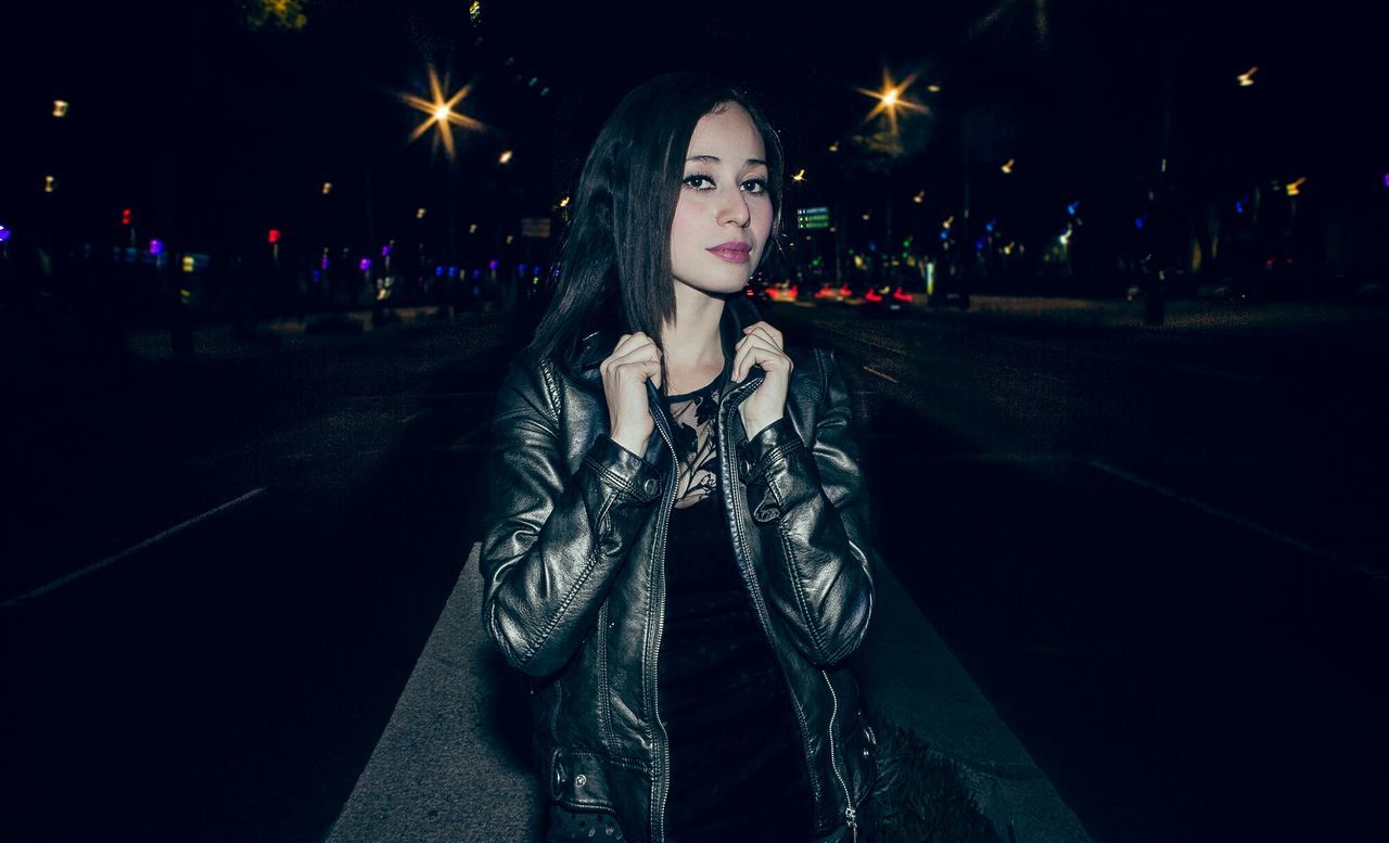 Portrait of beautiful young woman on street at night