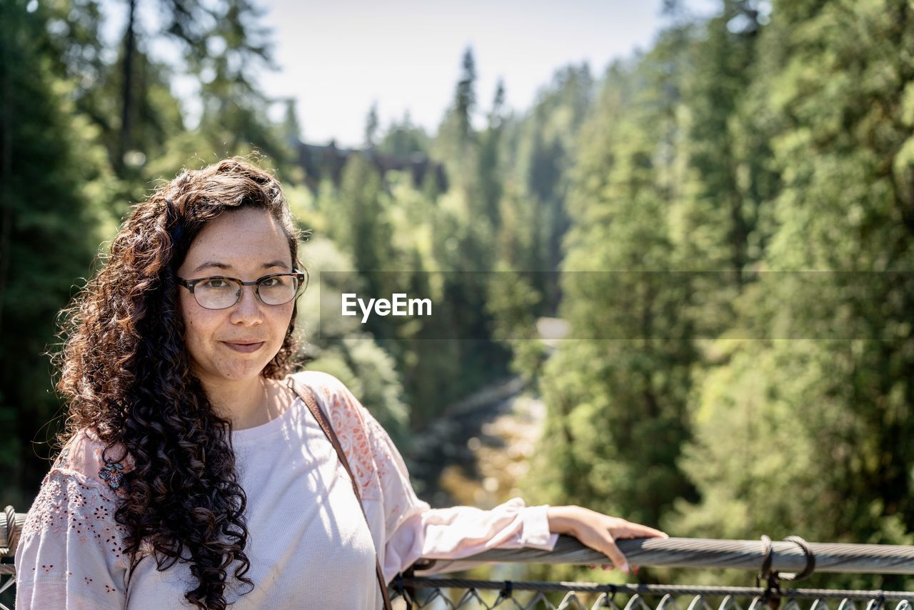 Pretty young woman poses in front of trees and bridges at the capilano suspension bridge