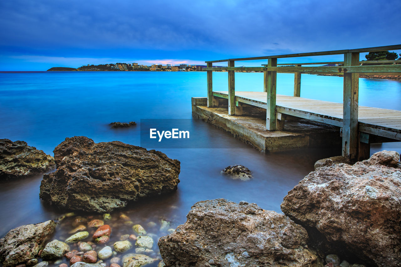 Scenic view of pier over sea against cloudy sky