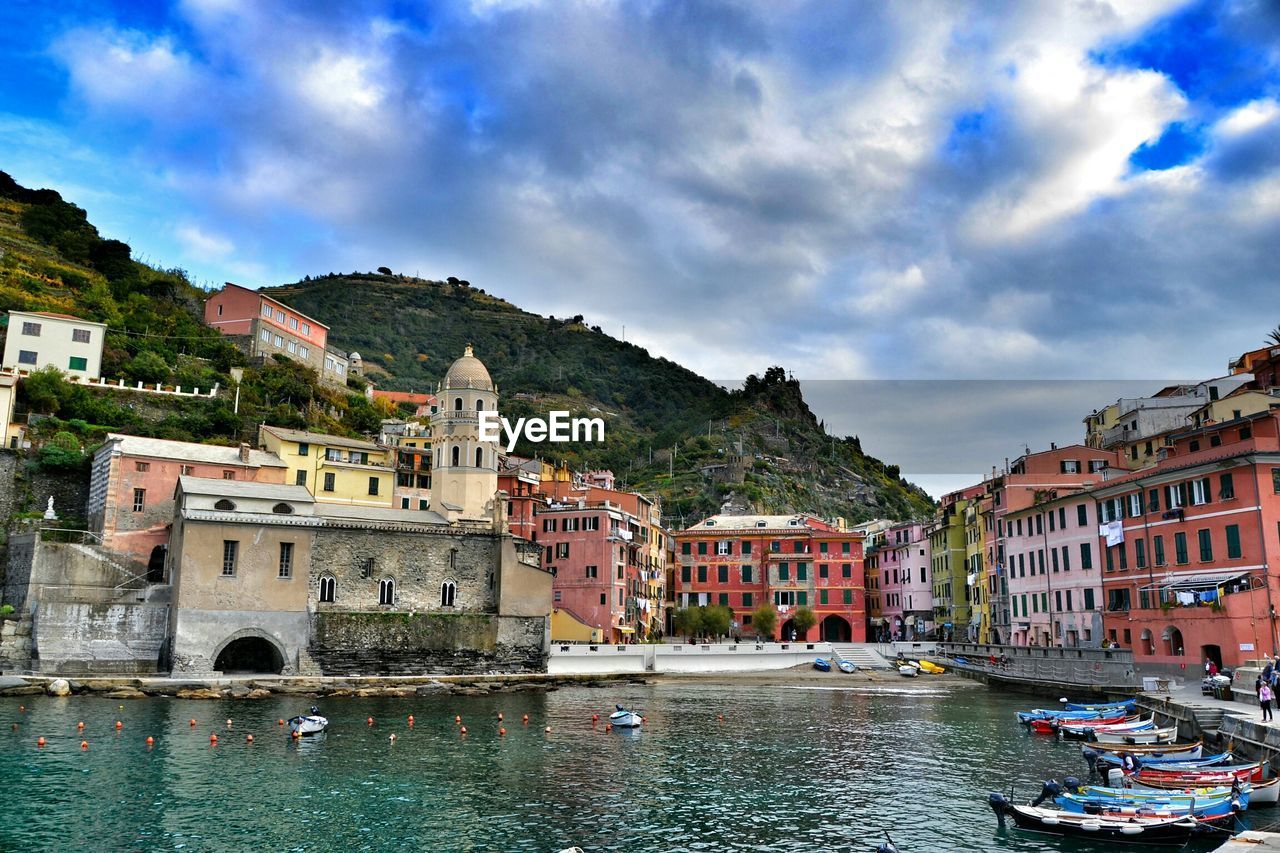 Boats moored in canal by buildings at cinque terre against sky