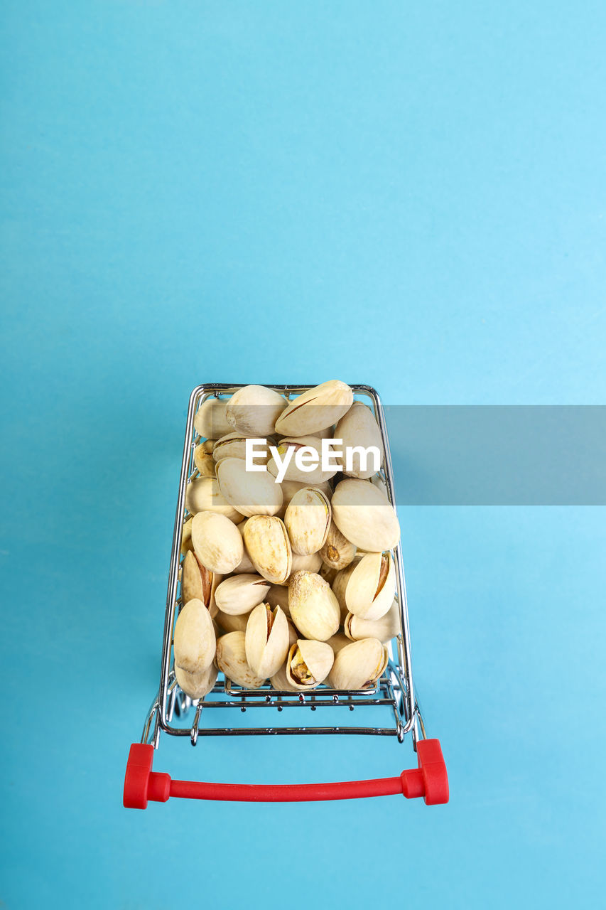 Food cart filled with pistachios in shells on a blue background. copy space vertical photo