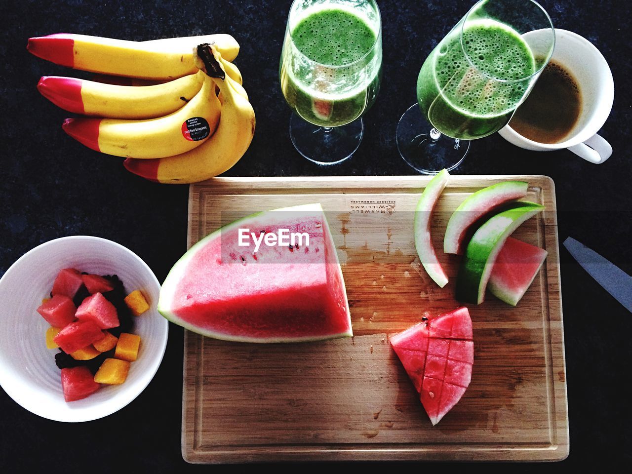 High angle view of chopped fruits with cutting board and drink on table