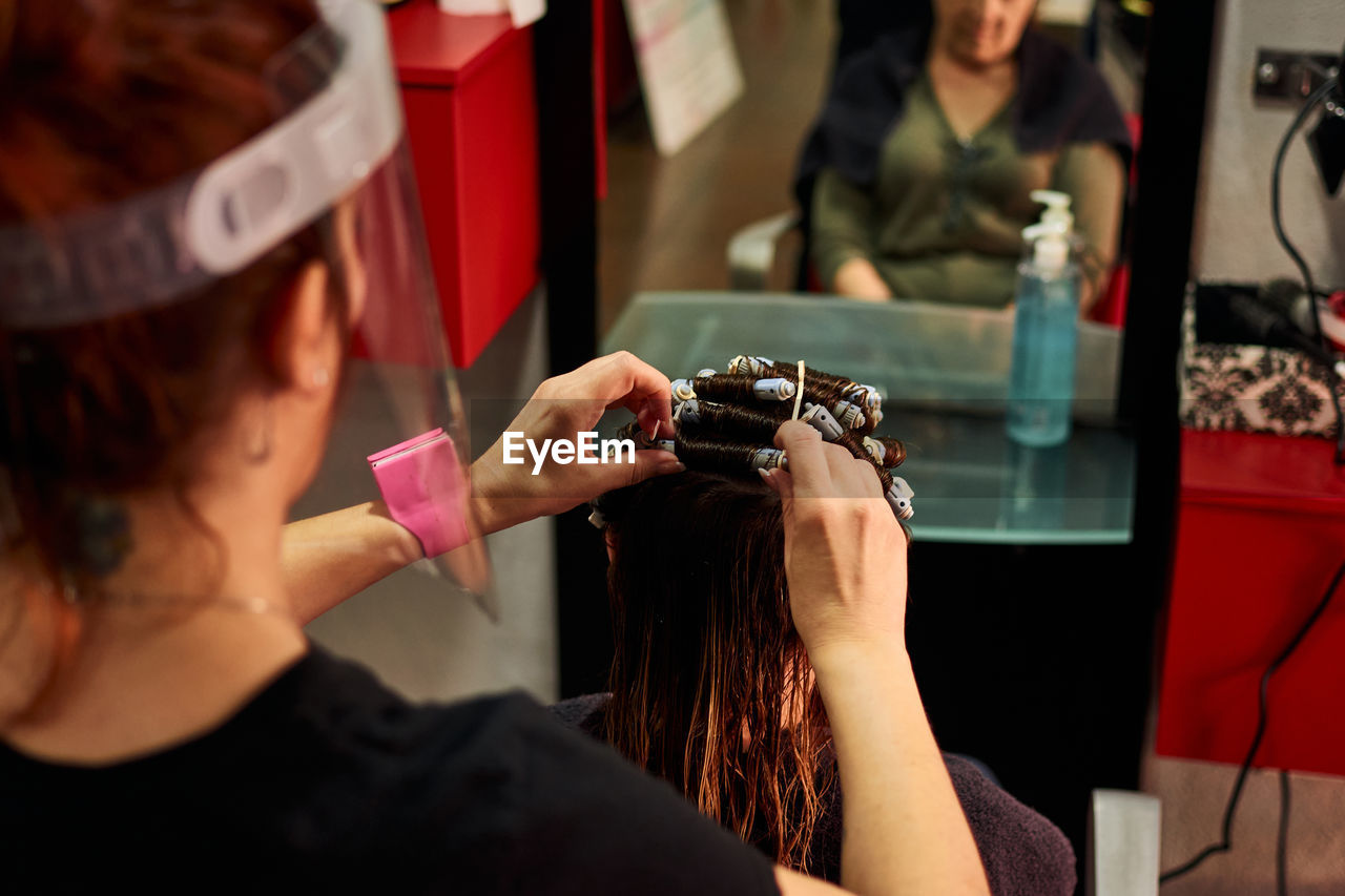 A close-up of a hairdresser combing a client with a face shield