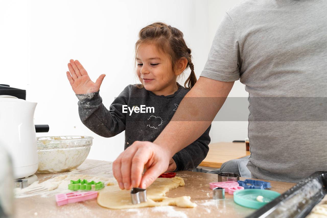 Midsection of father making cookie with daughter