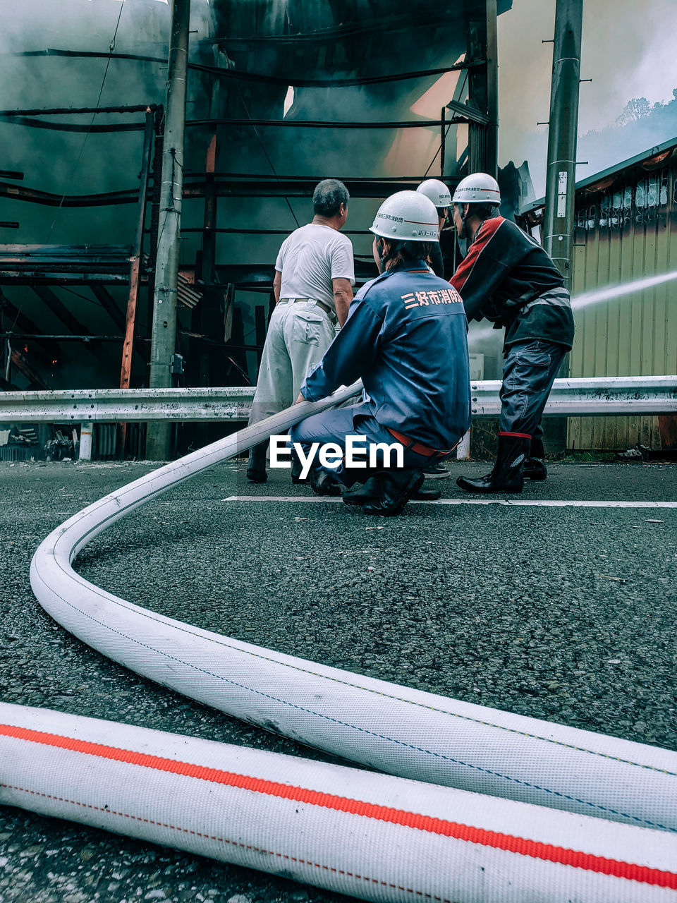 REAR VIEW OF PEOPLE WORKING ON MOTORCYCLE