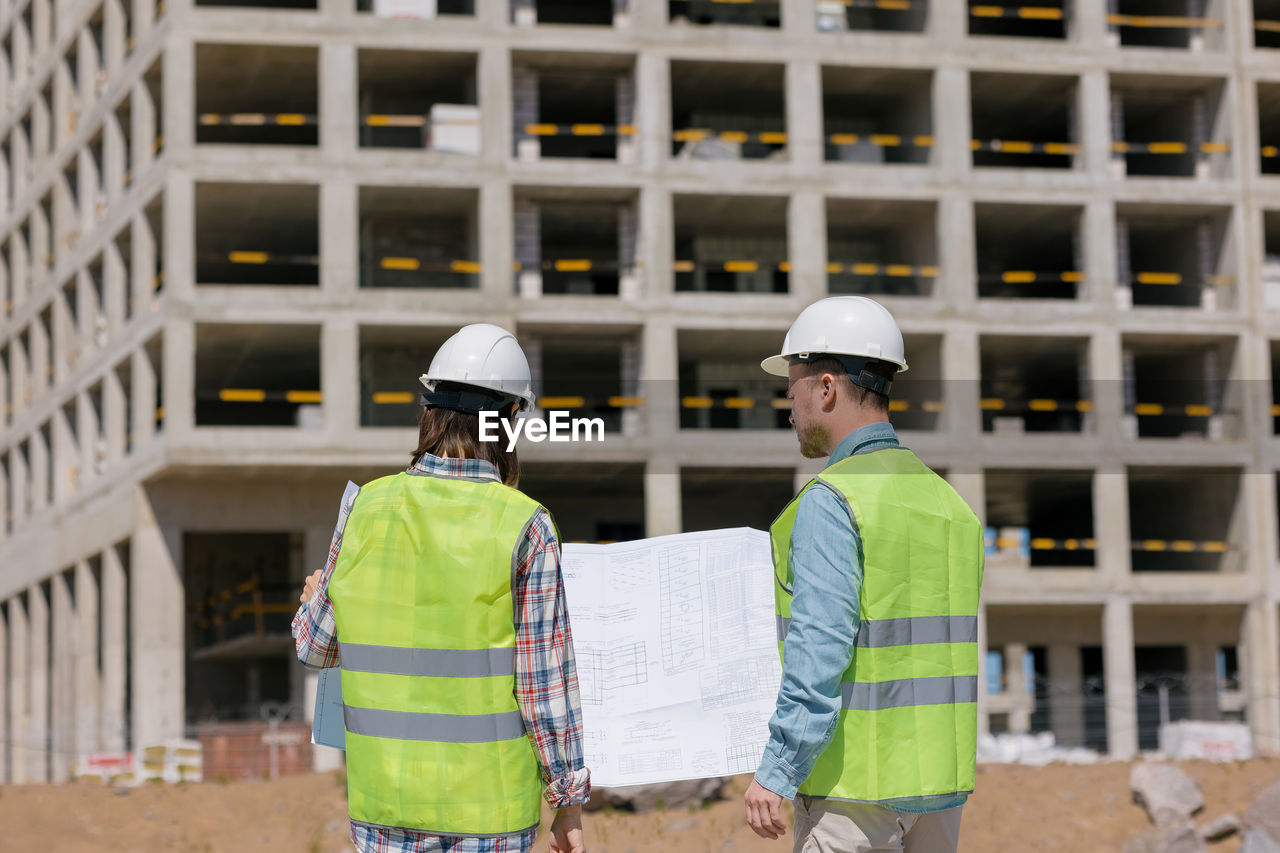 rear view of man wearing hat standing against building