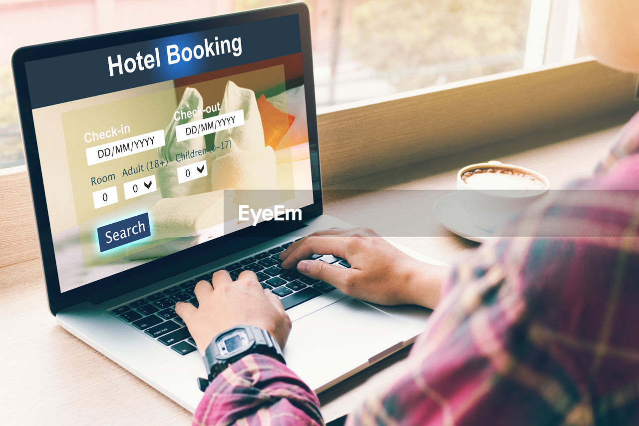 Close-up of businessman booking hotel room while using laptop