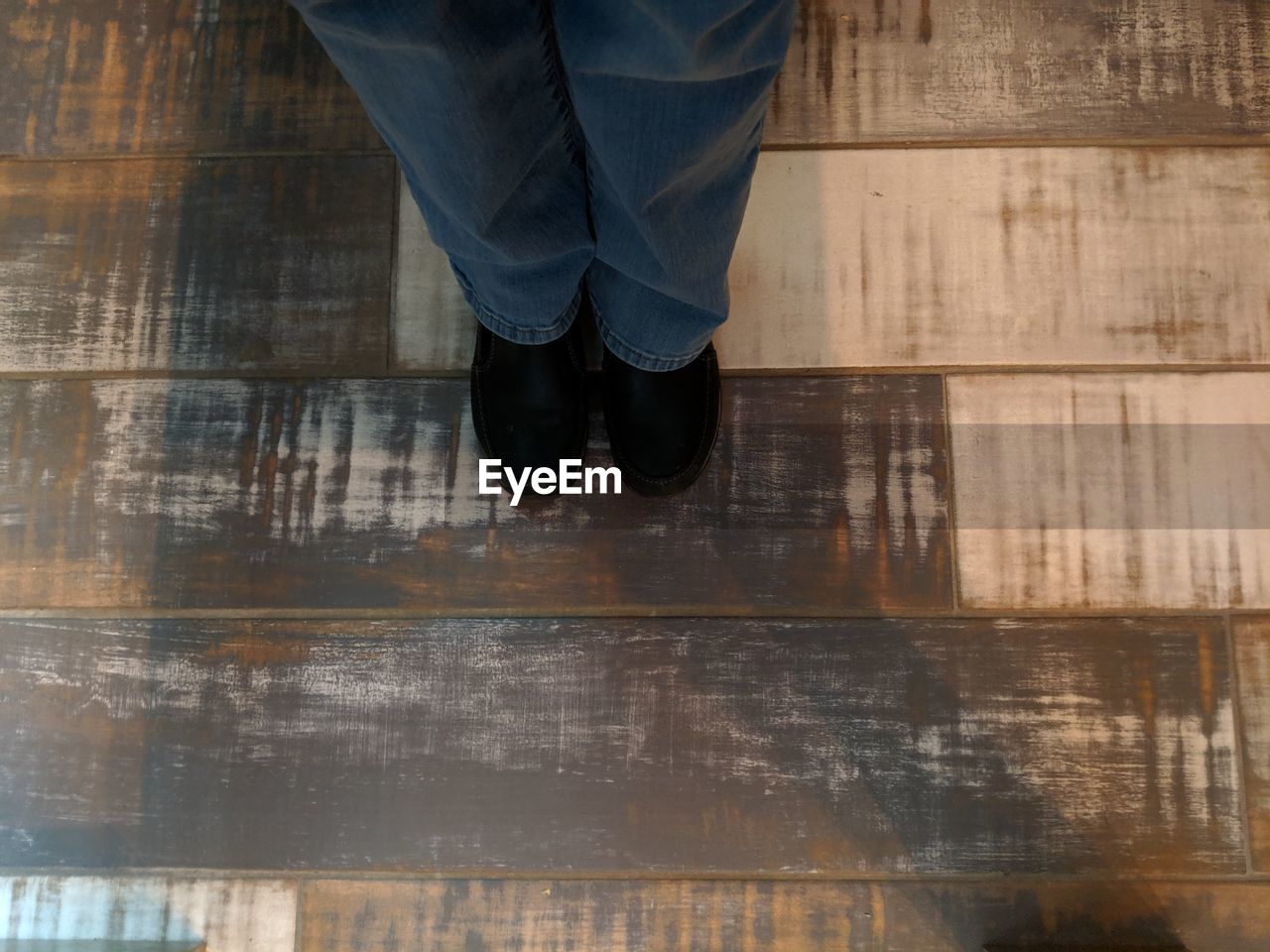 Low section of man standing on wooden floor