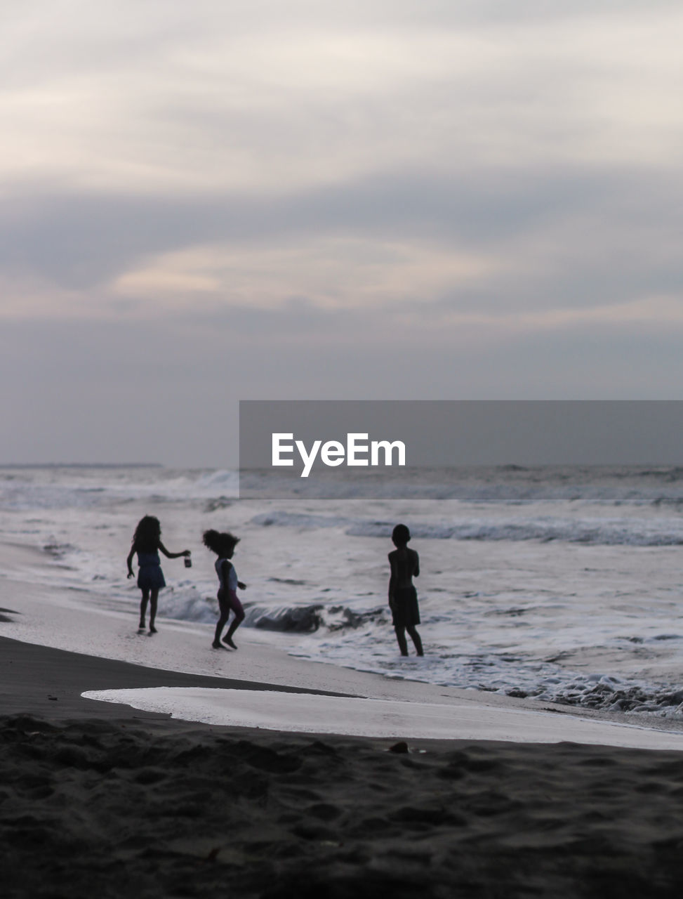 MEN AT BEACH AGAINST SKY