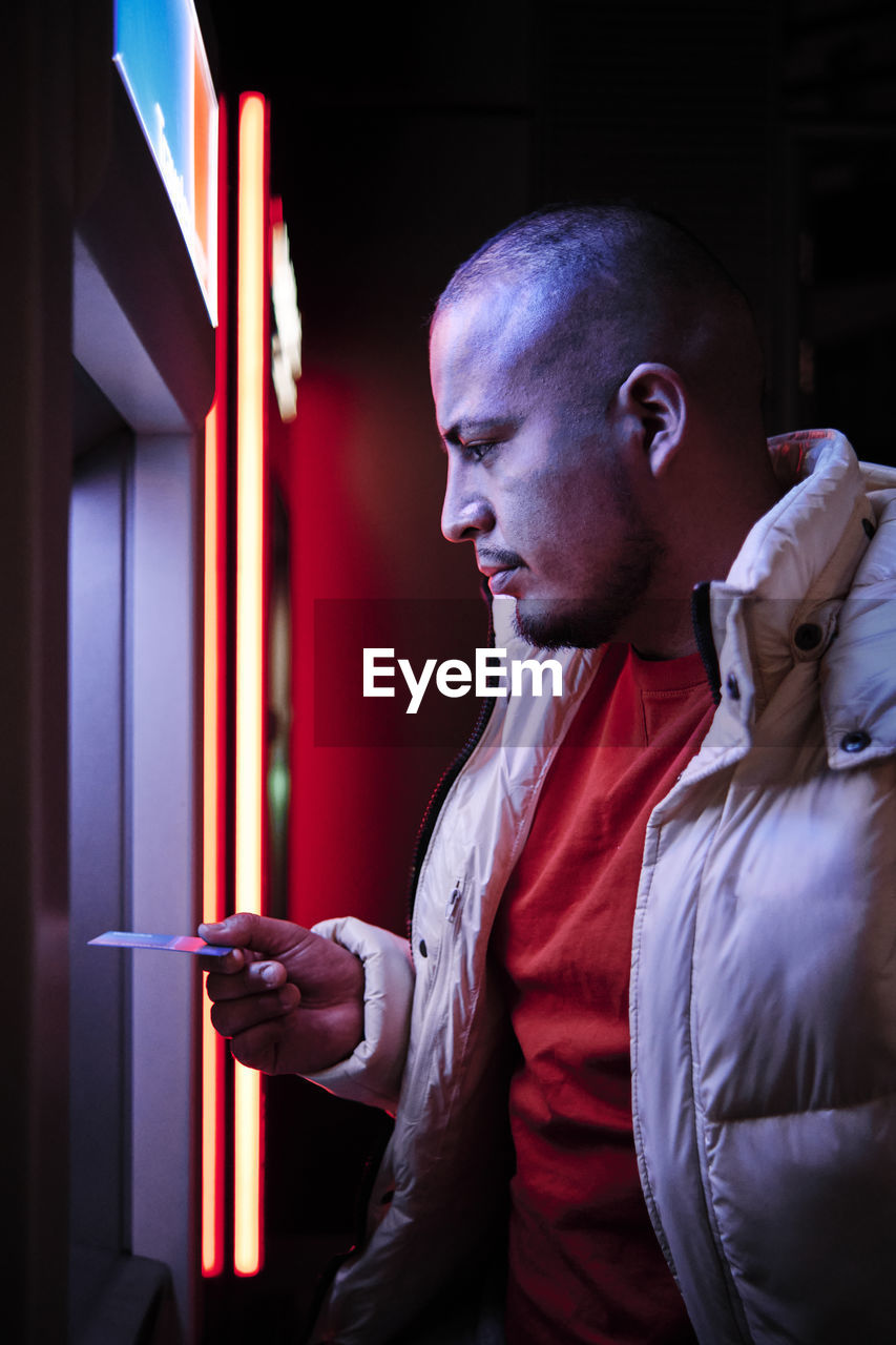 Young man using debit card at atm