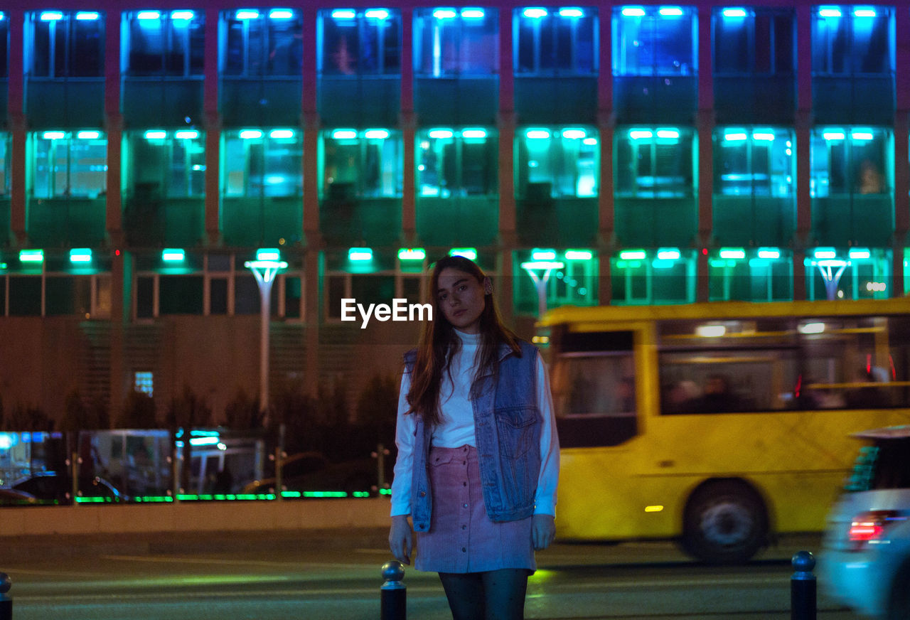 Portrait of young woman walking on city street at night