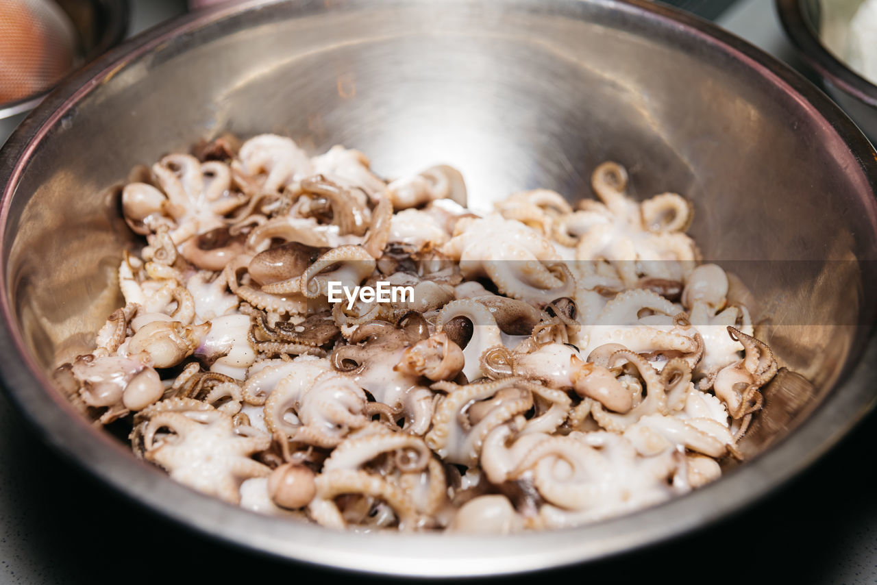 Small raw octopuses in a bowl. defrosted thawed cephalopods. close-up. selective focus.
