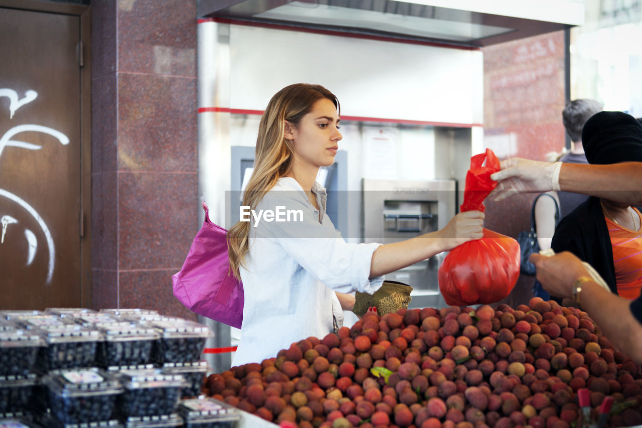 Woman buying fruits at market stall