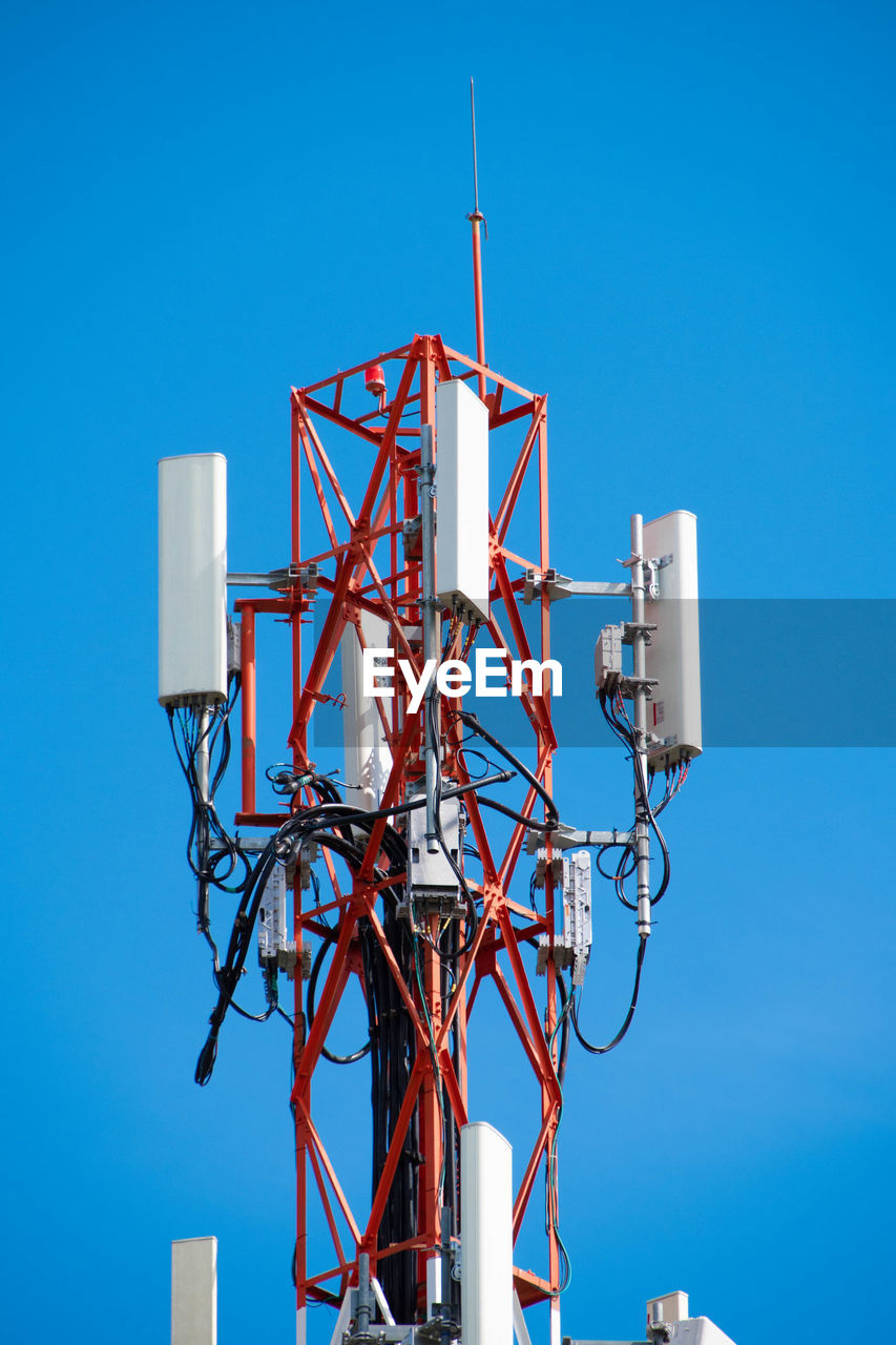 Low angle view of electricity pylon against clear blue sky