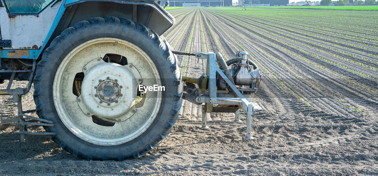 transportation, mode of transportation, tractor, agricultural machinery, vehicle, land vehicle, agriculture, day, land, field, wheel, machinery, road, farm, landscape, rural scene, nature, transport, asphalt, dirt, tire, agricultural equipment, outdoors, no people, sunlight, soil