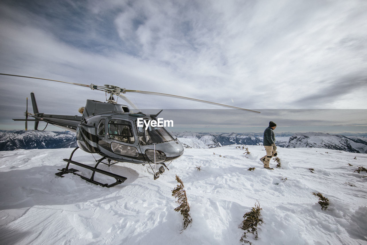 Helicopter pilot explores a snow-covered mountain summit.
