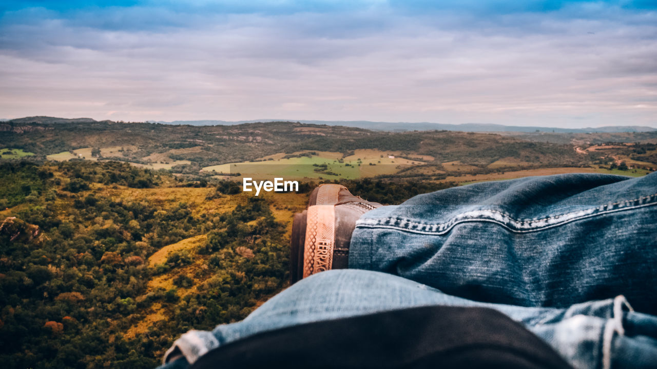 LOW SECTION OF MAN RELAXING ON ARID LANDSCAPE