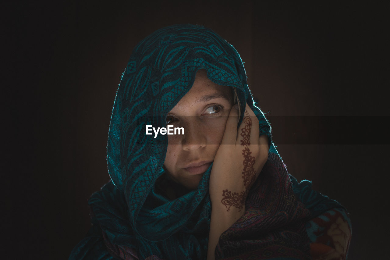 Portrait of young woman against black background