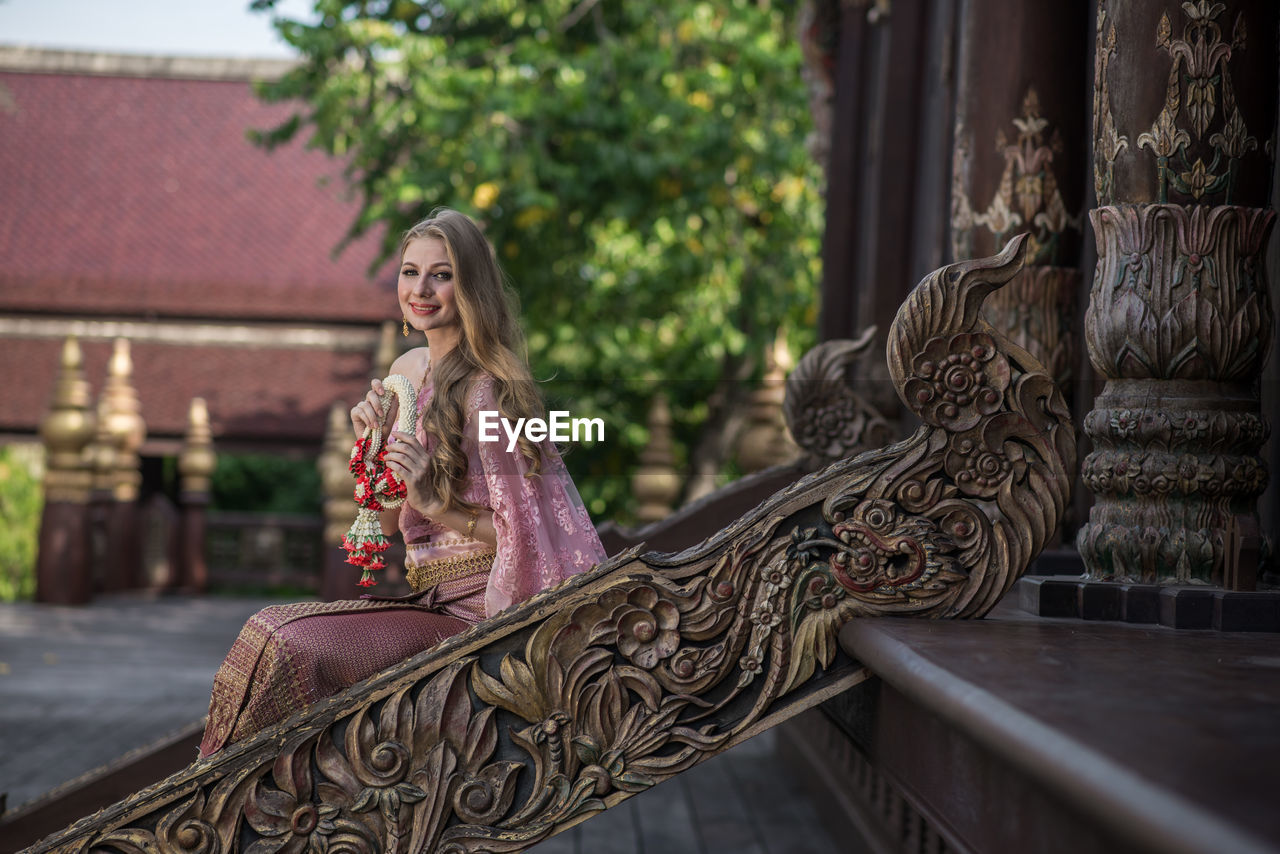 Portrait of smiling young woman sitting outdoors