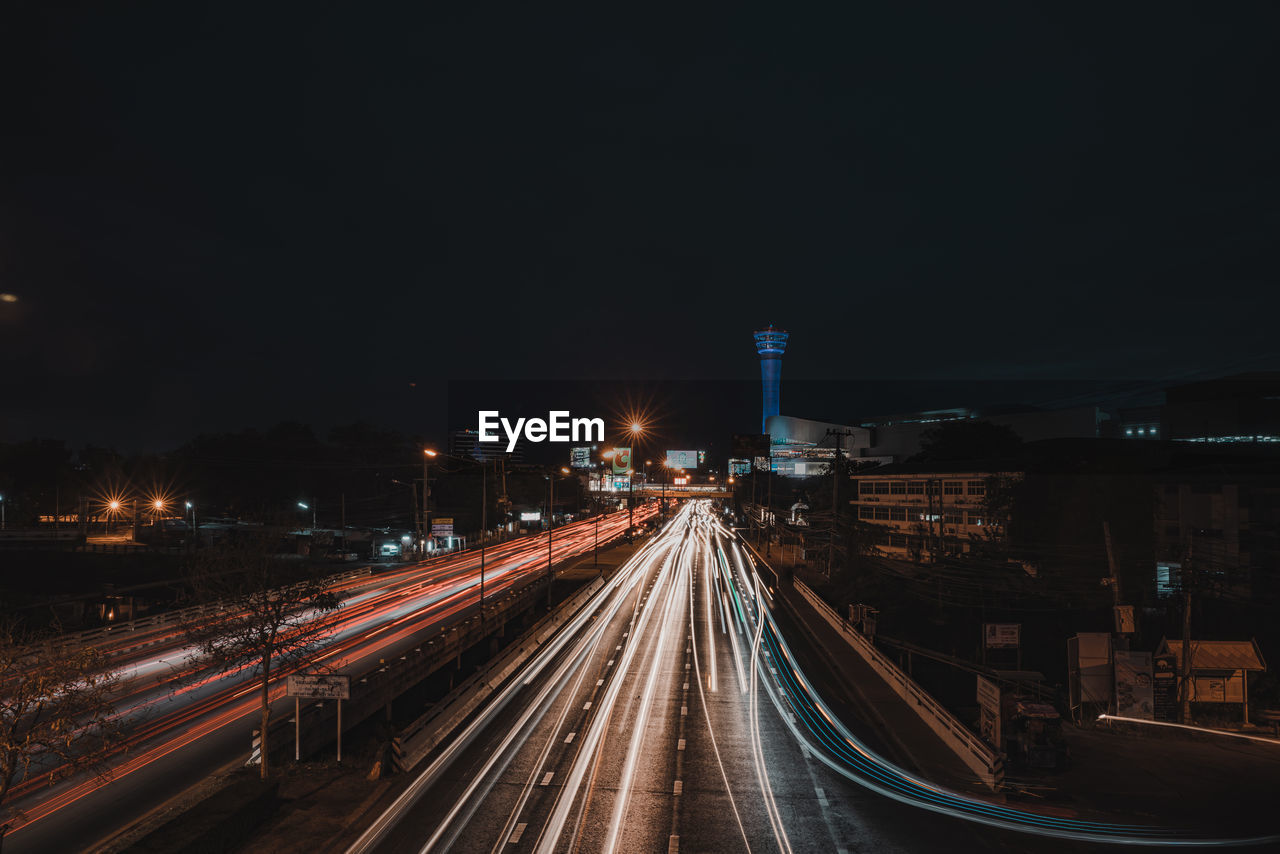 Light trails on road against sky at night