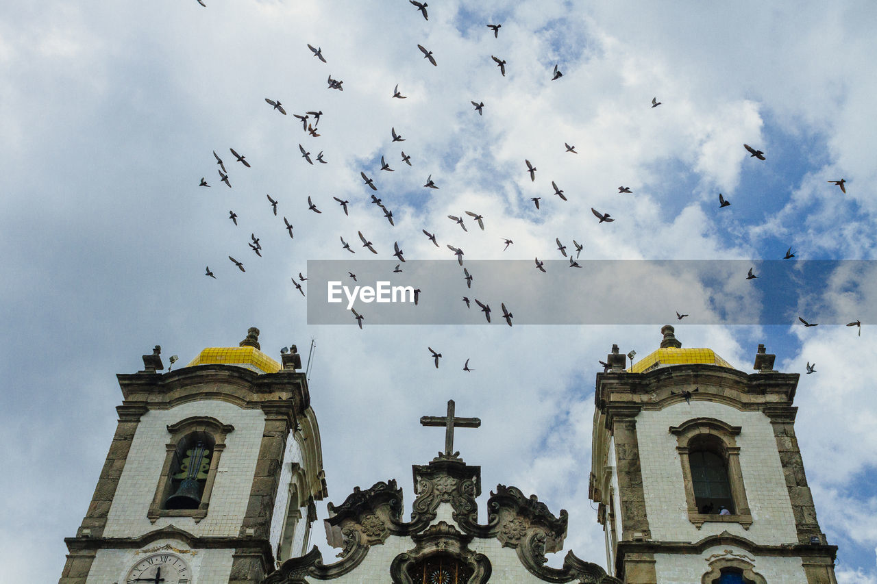 Birds flying over church of nosso senhor do bonfim against sky
