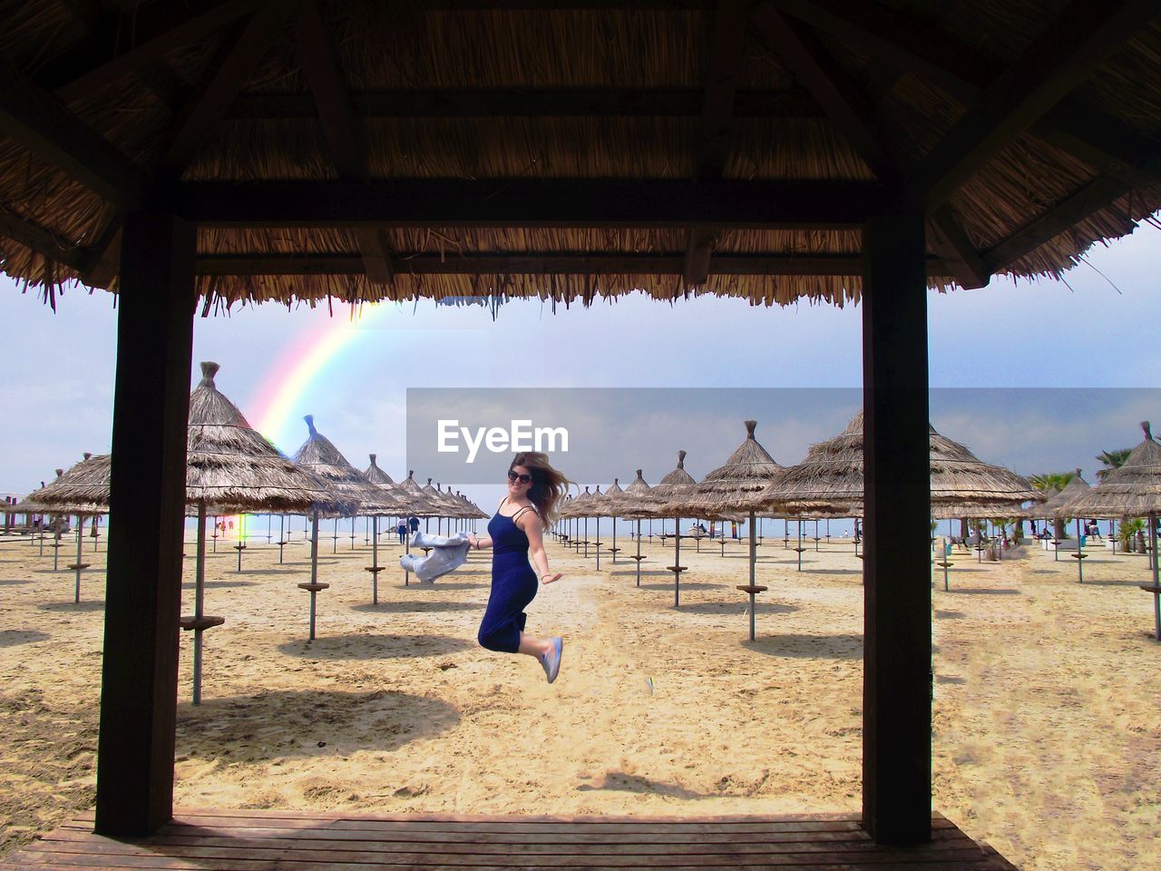 Full length of woman jumping on beach against sky