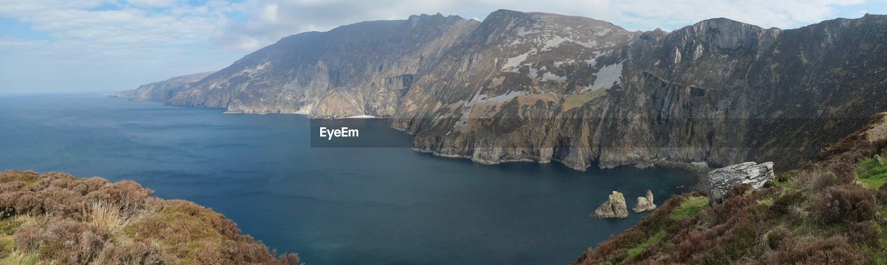 Scenic view of sea and mountains against sky