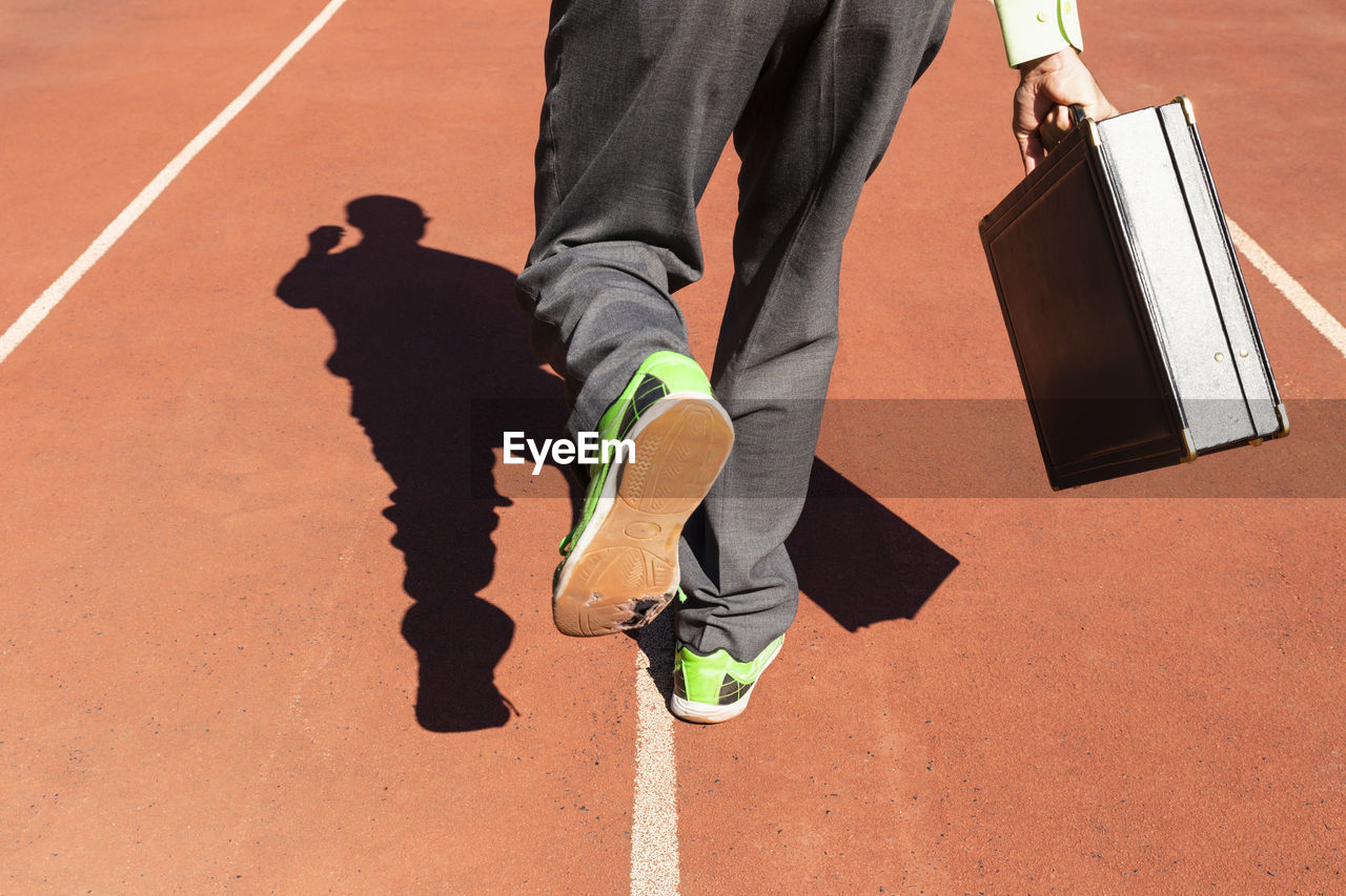 Low section of man running with briefcase on track