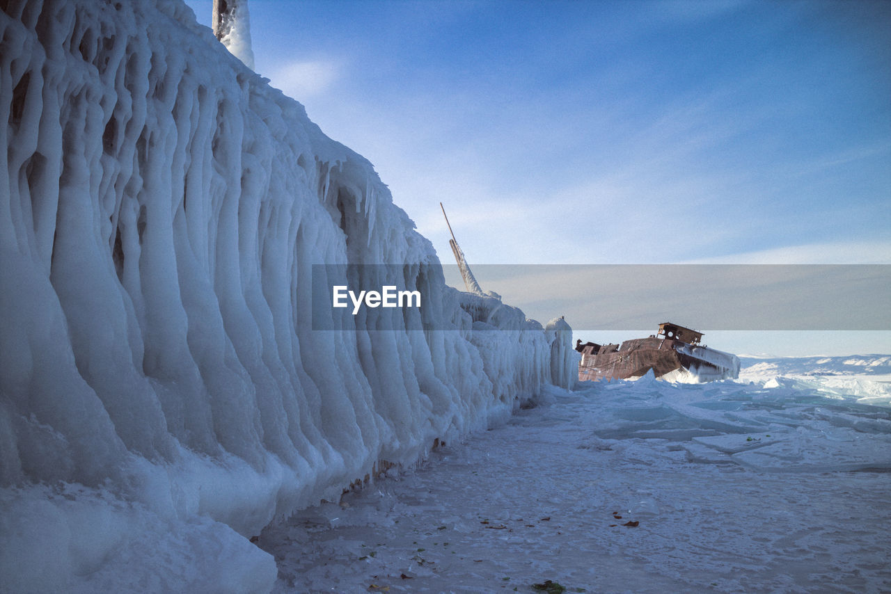 Shipwreck on frozen lake against sky