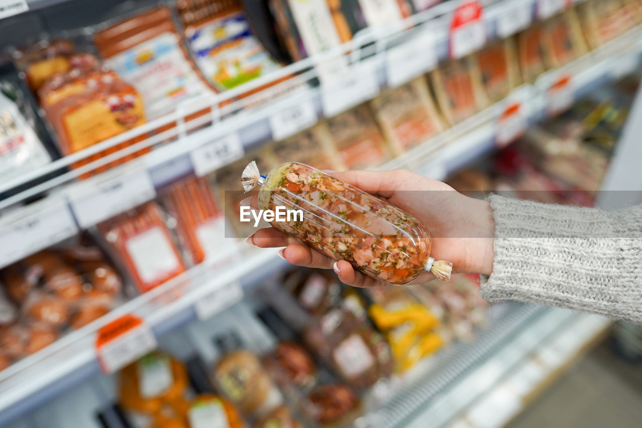 Woman chooses a sausage in vacuum package at the grocery store