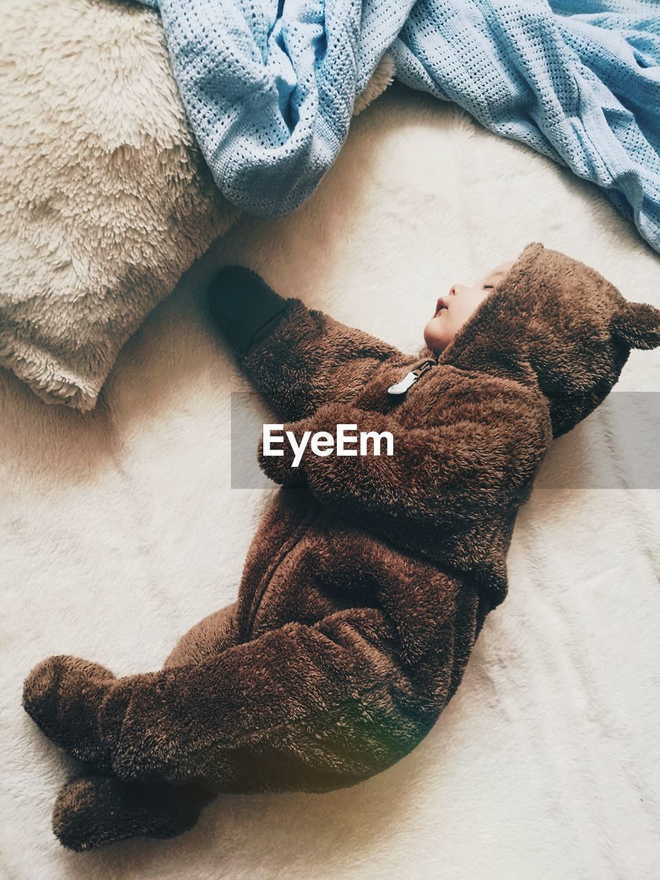 High angle view of baby in bear costume sleeping on bed