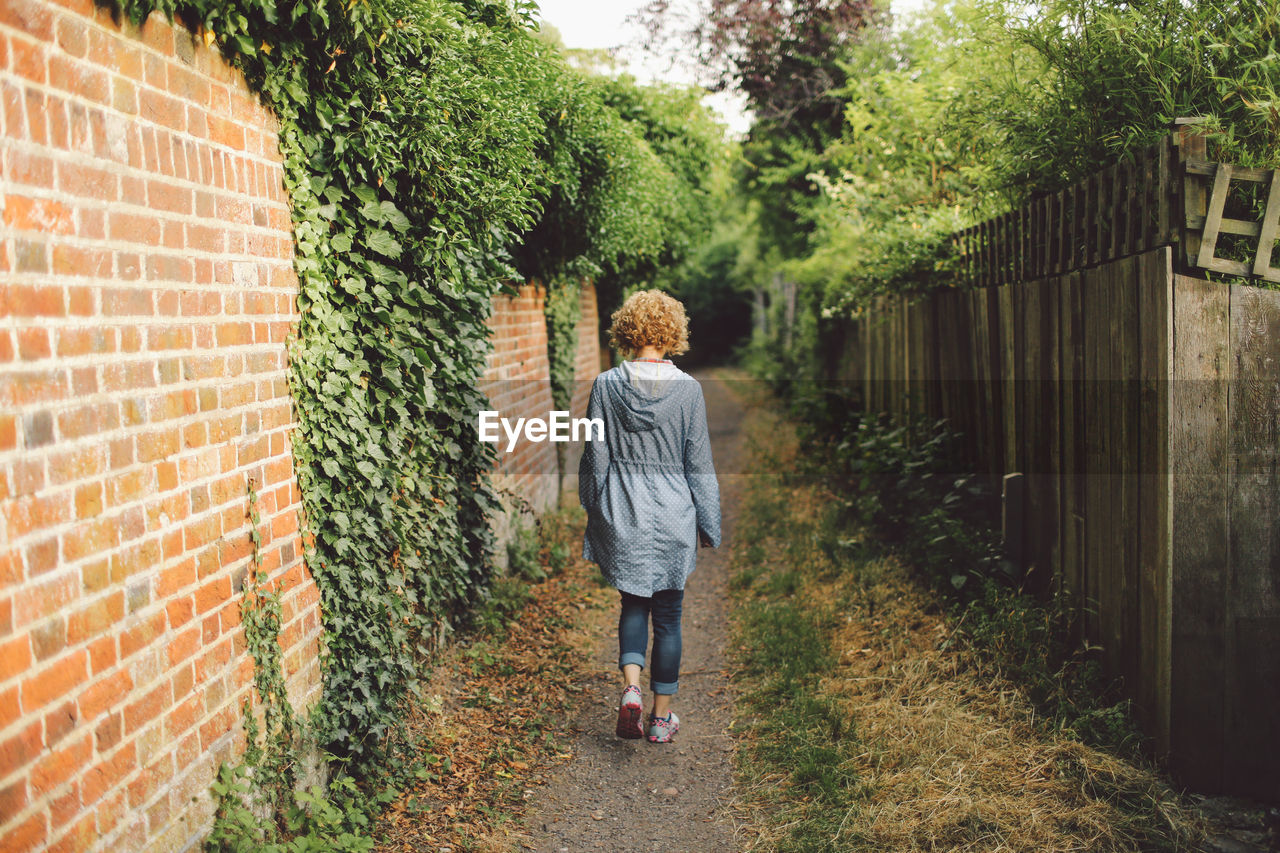 Rear view of young woman walking on footpath