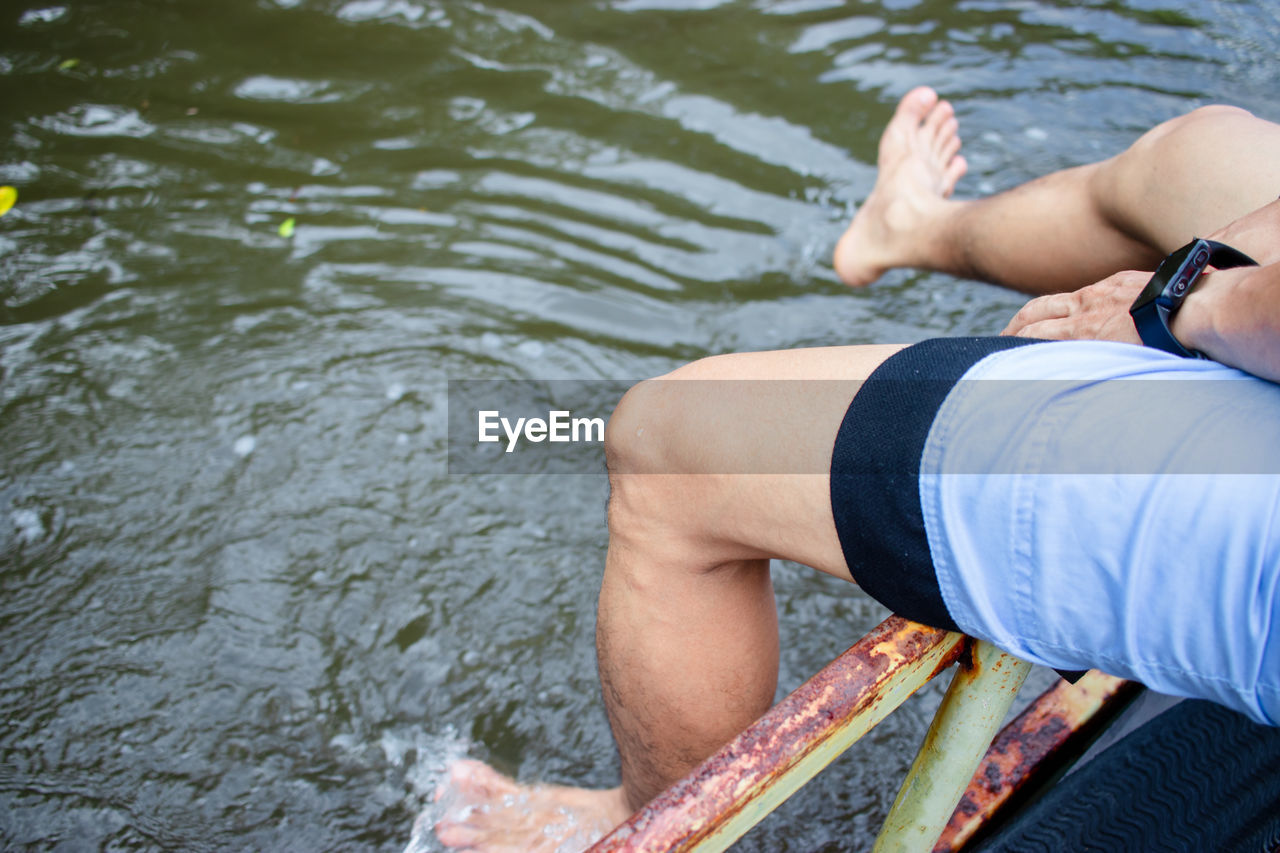 Low section of man relaxing over lake