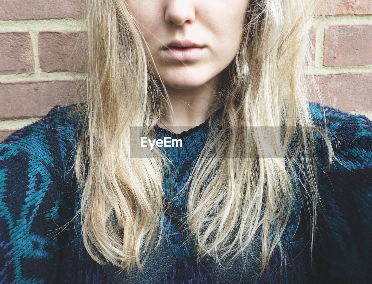 Cropped image of woman against brick wall