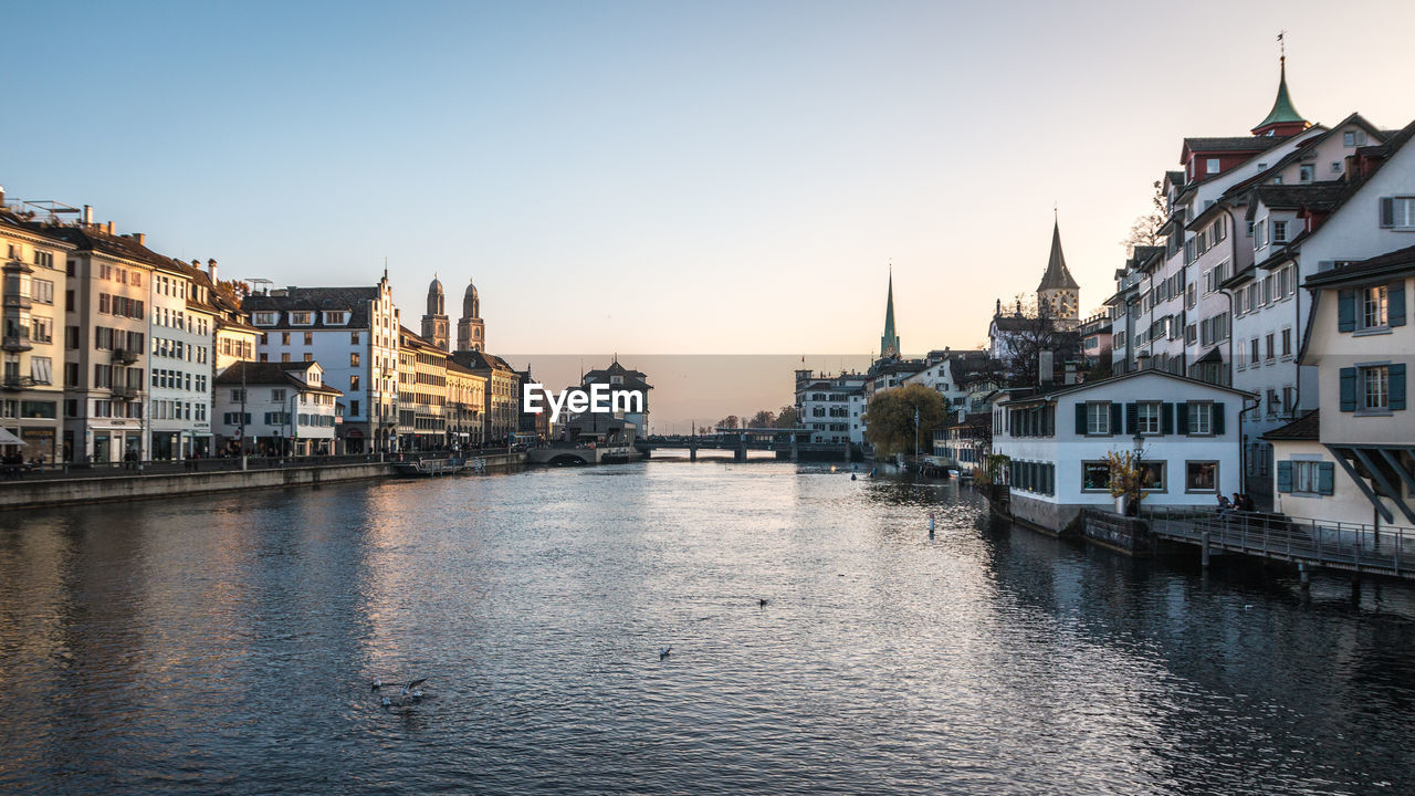 Scenic view of river amidst buildings against clear sky