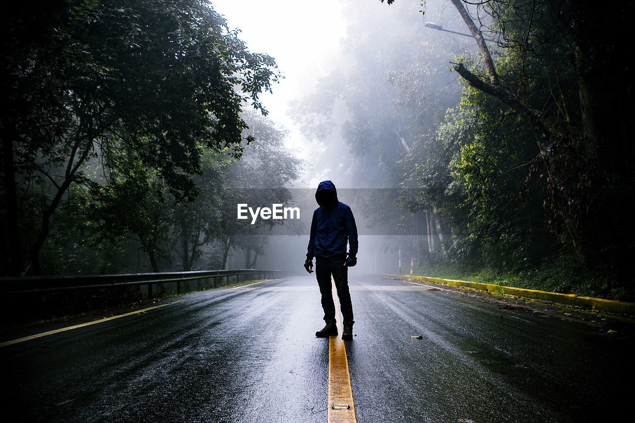 A man standing on empty road during foggy weather