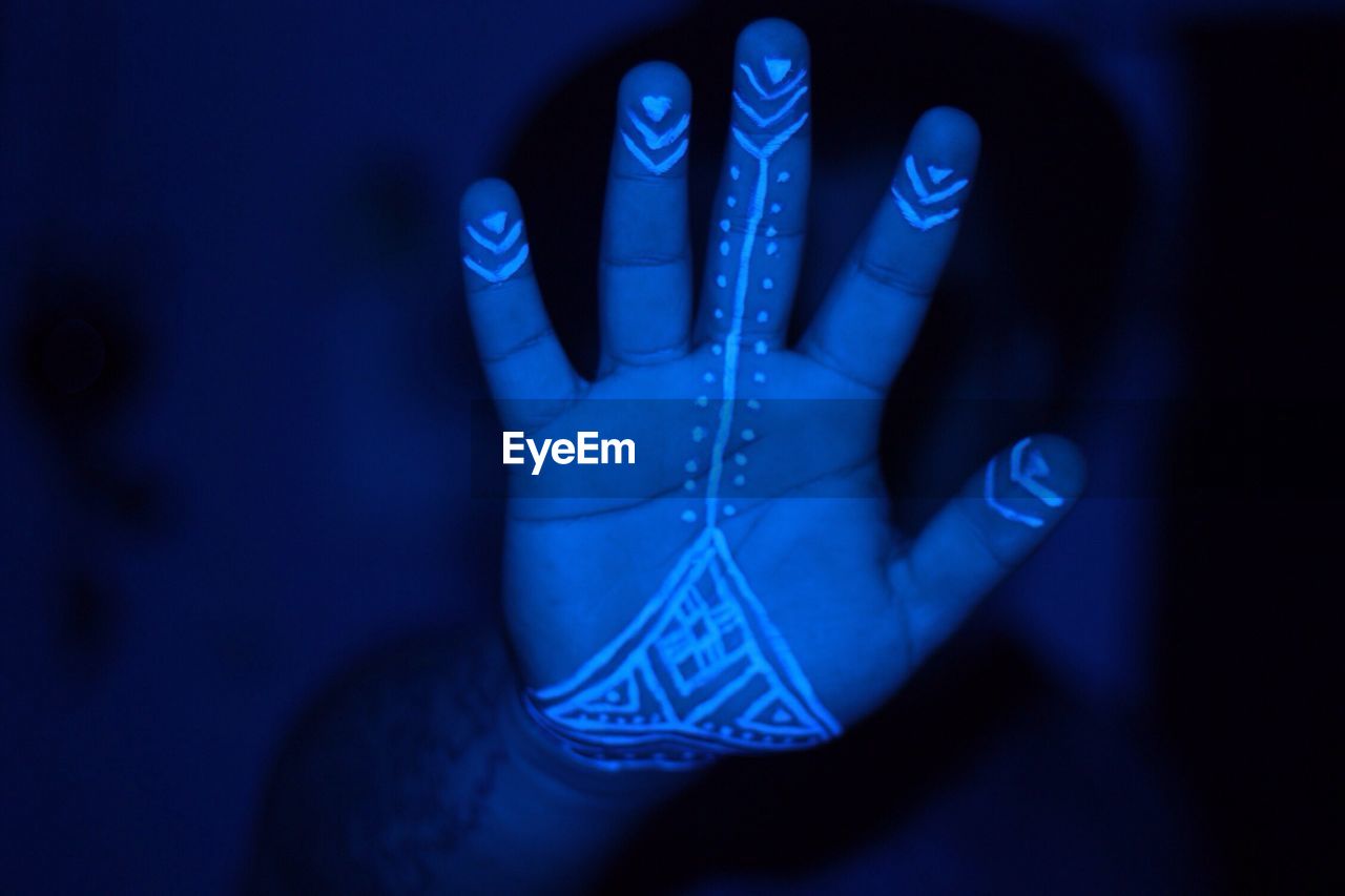 Cropped image of hand with henna tattoo in darkroom