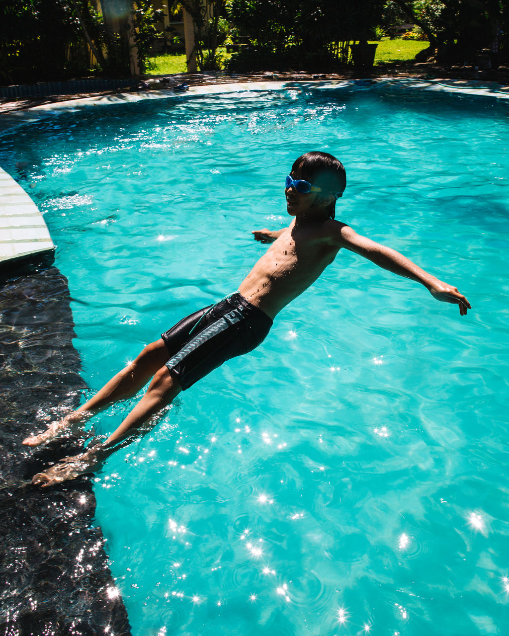 High angle view of shirtless boy jumping in swimming pool