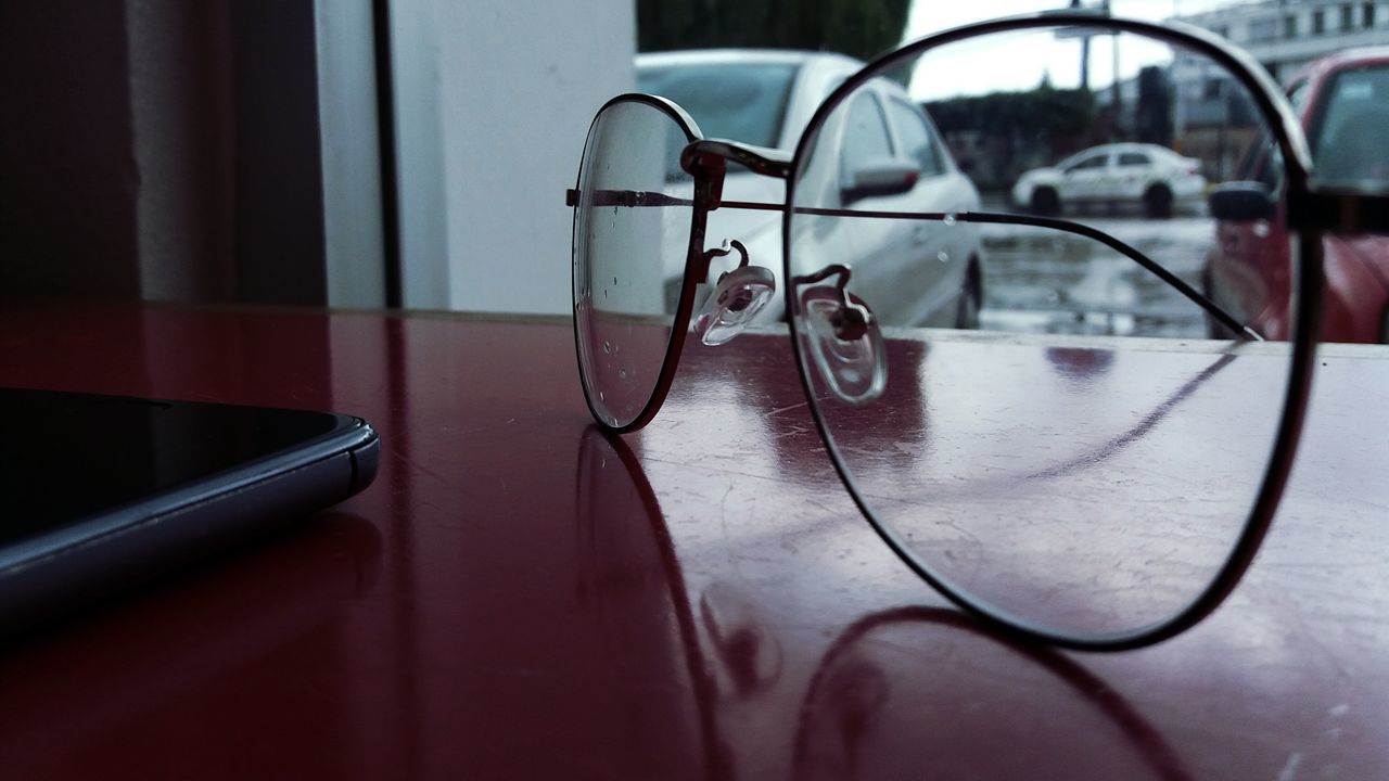 CLOSE-UP OF EYEGLASSES ON TABLE AGAINST WINDOW