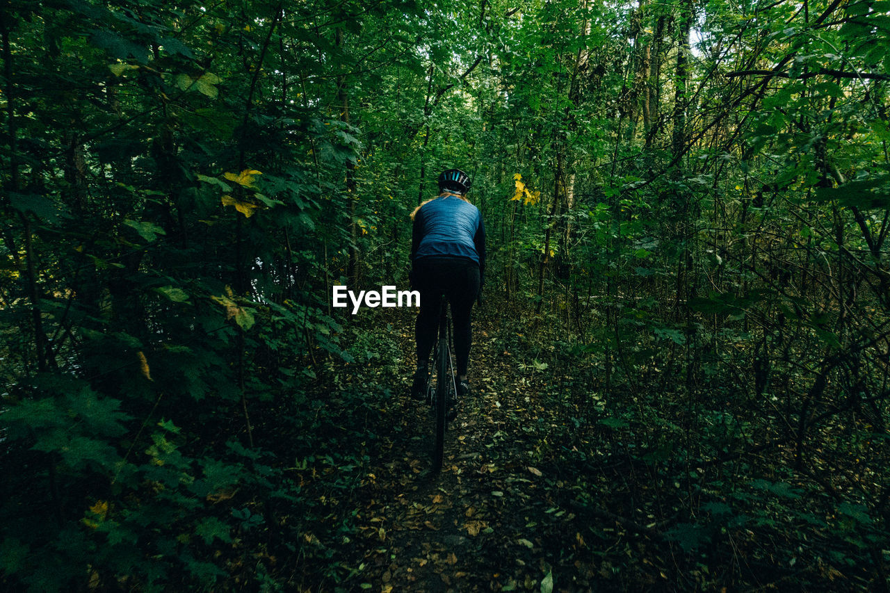 Rear view of woman cycling in forest