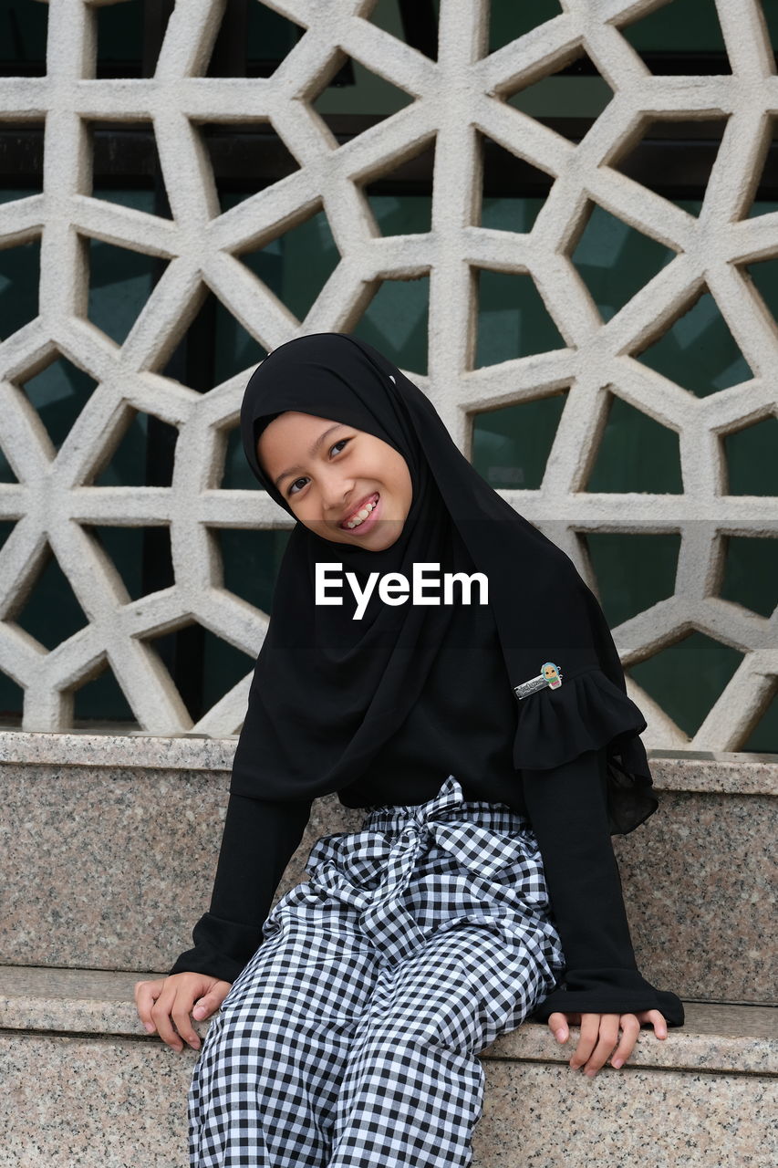 A happy face of an asian girl sitting nearby the lake at the landmark of putrajaya malaysia